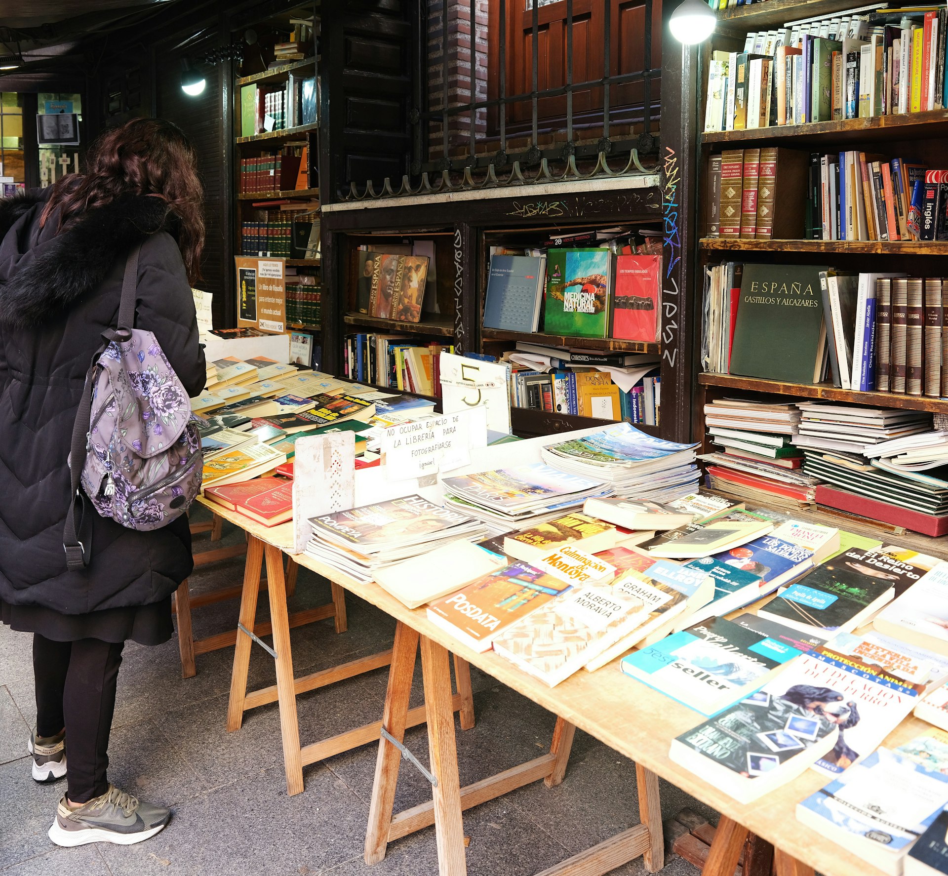 a woman standing in front of a table filled with books